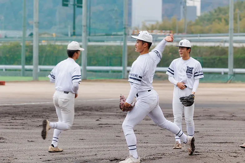 学校のグラウンドで、野球部の学生たちが投球練習に取り組む部活動の様子