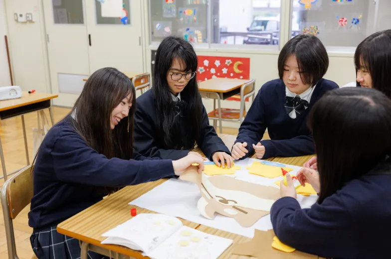 教室で学生たちが机を囲み、話し合いながら制作課題に取り組んでいるグループ学習の様子