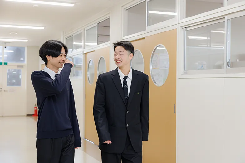 校舎内の廊下で、学生同士がリラックスした様子で会話をしている休み時間の風景