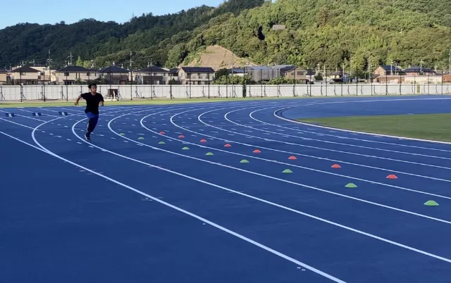 陸上部員が陸上トラックを走っている様子