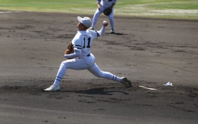 野球場で、投手が投球後に腕を振り抜いている様子