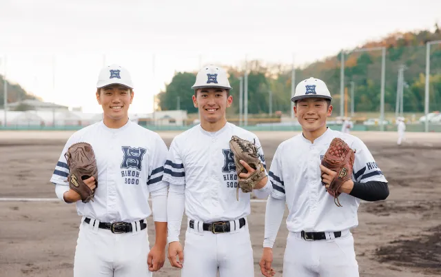 野球場で、ユニフォーム姿の野球部員が並んで立っている様子