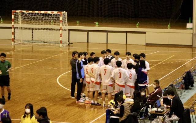 屋内の体育館で、ハンドボール部の部員が整列している様子