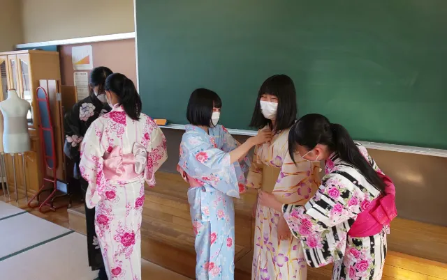 浴衣姿の部員同士が帯の位置を確認し合いながら着付けをしている様子