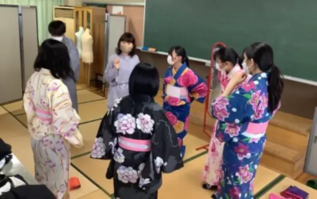 浴衣を着た部員が輪になり、着付けの手順について話し合っている様子