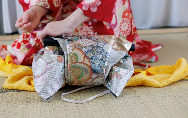 帯をたたみ、結びの形を確認している部員の手元