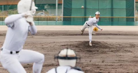 野球部で、屋外のグラウンドで投手がボールを投げているプレーの様子