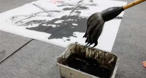 墨を含ませた筆を使い、紙の上に文字を書いている書道の作業の様子