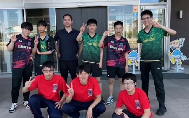 卓球部の部員が集合し、カメラに向かってポーズを取っている様子