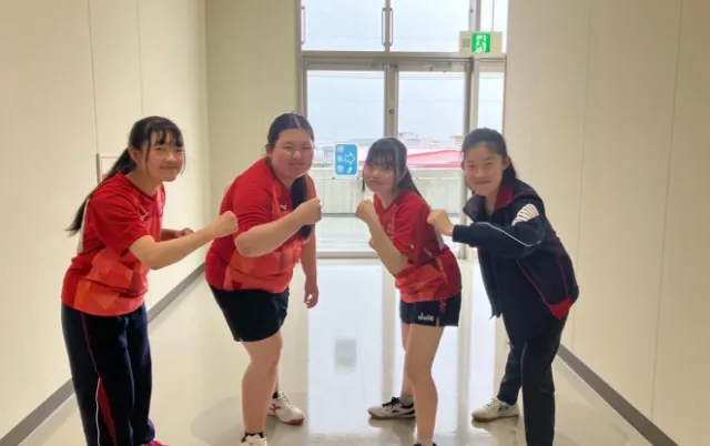 卓球部の部員が並び、笑顔でポーズを取っている様子