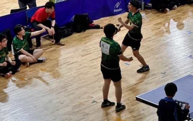 緑色のユニフォーム姿の部員2人がプレーしている様子