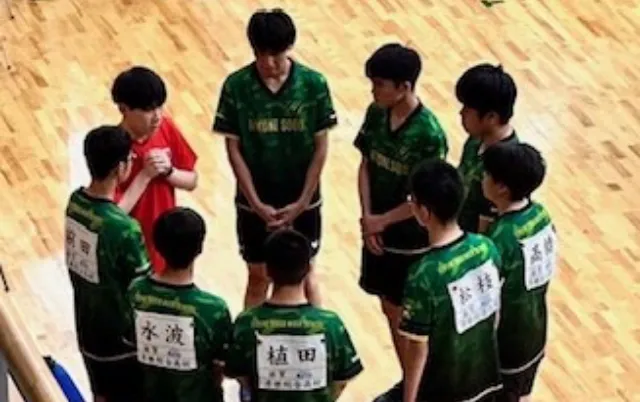 緑色のユニフォーム姿の部員が円になって集まっている様子