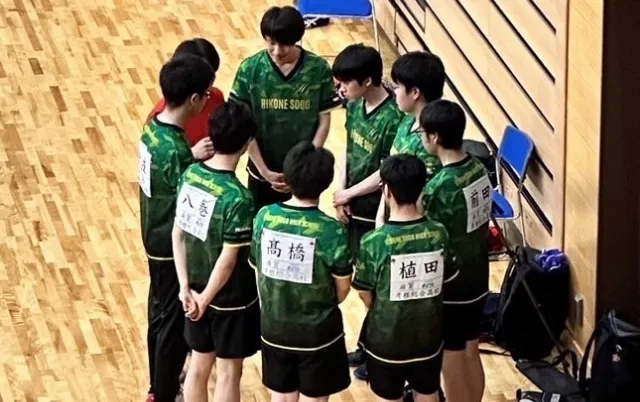 緑色のユニフォーム姿の部員が集まり、輪になって話している様子